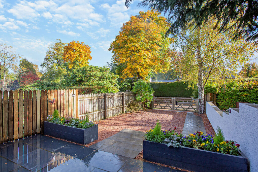Gravel driveway at Highfield Lodge with planted borders, timber fencing and gate entrance.