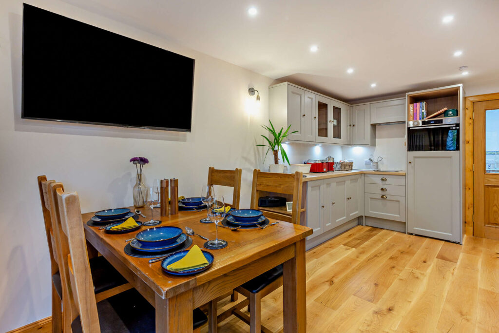 Open-plan kitchen and dining area at Highfield Lodge with dining table for four and fitted kitchen.