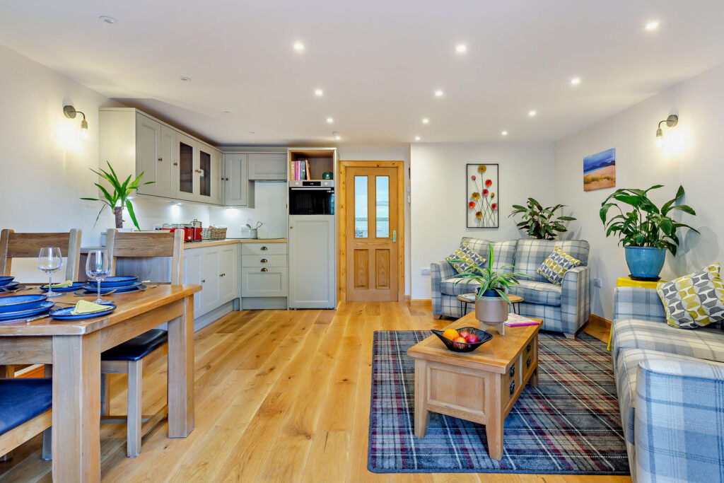Open-plan living space at Highfield Lodge with lounge, dining area and glazed doors to the patio.
