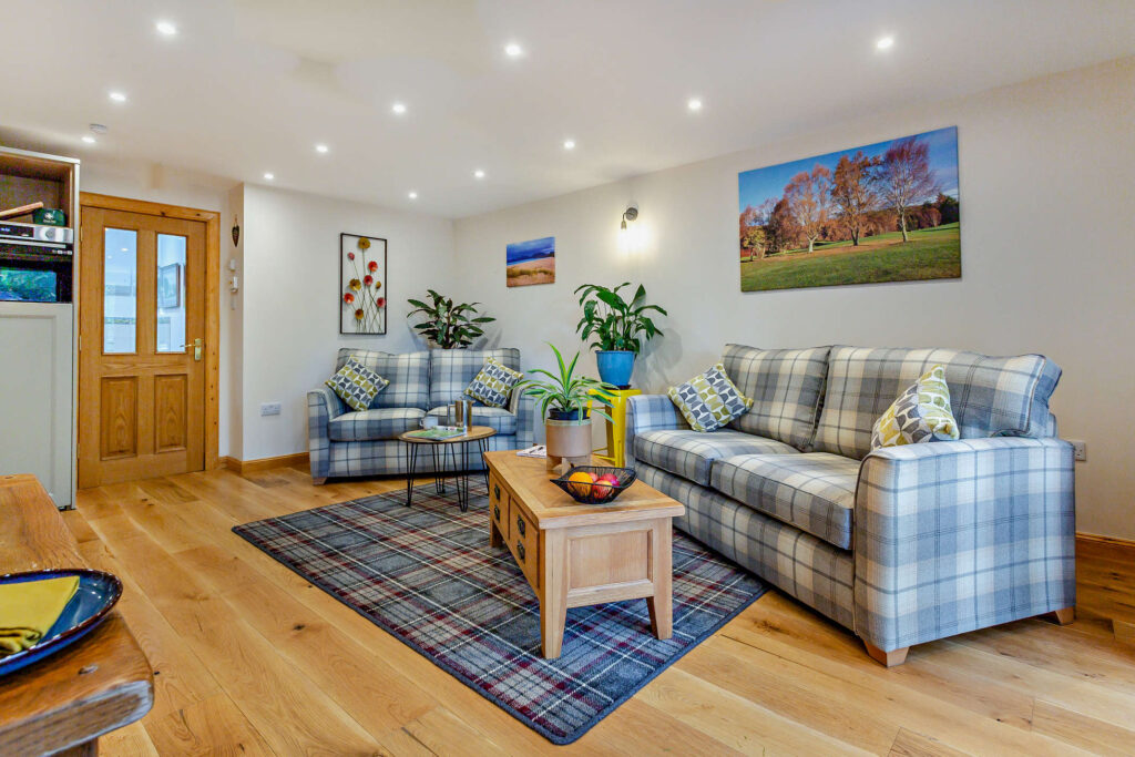 Sitting area at Highfield Lodge with tartan sofas, coffee table and open-plan layout.