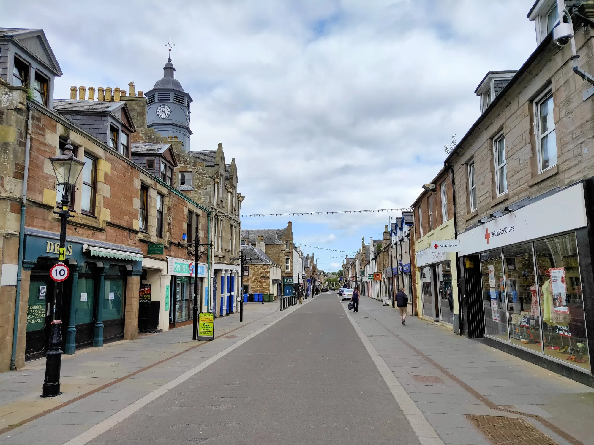 Contemporary view looking east along Dingwall High Street, with shops lining both sides of the road.