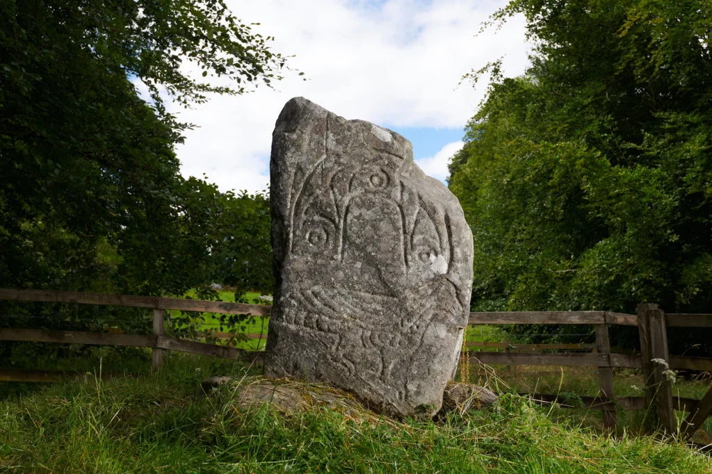 The Eagle Stone in Strathpeffer, a carved Pictish standing stone surrounded by trees and a wooden fence.